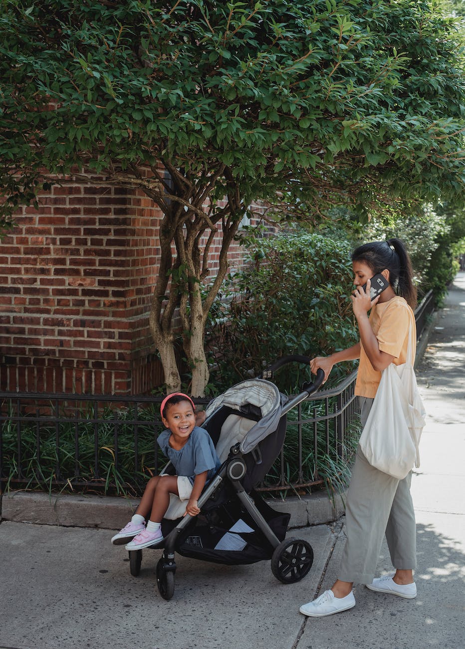 ethnic woman pushing carriage on street